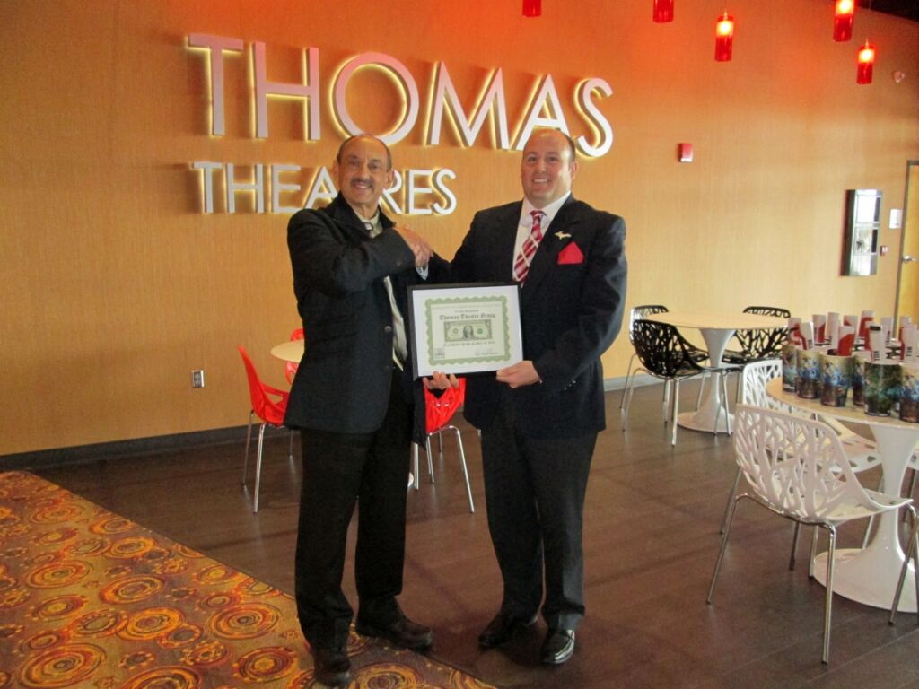 Frank Stabile, Chairman of the Marquette Township Business Association, presenting First Dollar to Thomas D. Andes, president of the Thomas Theatre Group